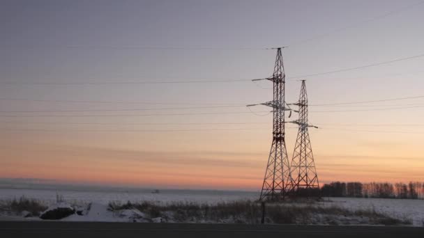 Towers with power transmission lines in wide snowy field — 图库视频影像
