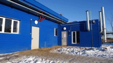 Karlı bahçenin arasında pencereleri ve bacaları olan mavi atölye