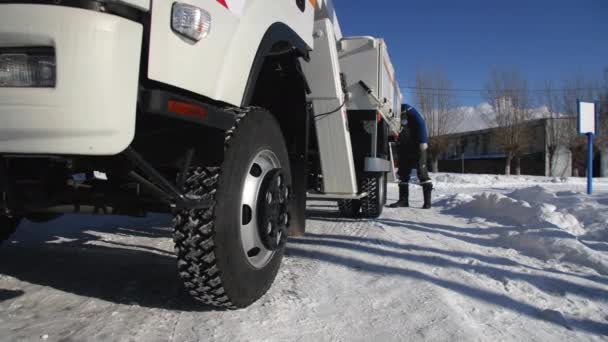 Zaměstnanec klade blokovou podporu pod kolečko kamionu v zimě — Stock video