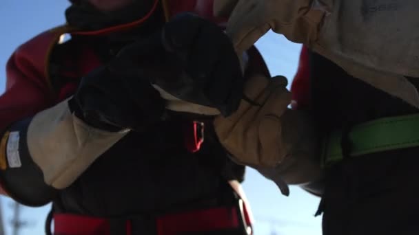 Elektryk pomaga koledze założyć rękawiczki w zimowy dzień — Wideo stockowe