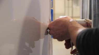 İşçi atölyedeki buzdolabının üzerine metal parçaları yerleştiriyor