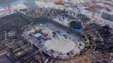 İnşaat alanındaki karlı zeminde insanlar ve makineler
