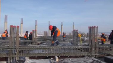 Çalışan, kış günü inşaat alanında metal çubuk alıyor.