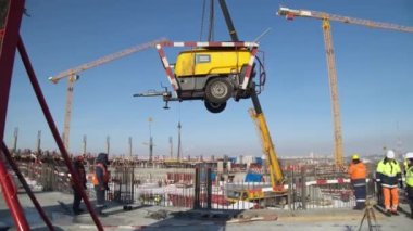 Kamyon vinci karlı şantiyedeki sarı makineyi kaldırdı