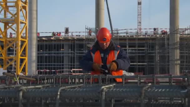 Starší zaměstnanec kroutí drát na jatečně upraveném těle na staveništi — Stock video