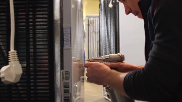 Pracownik mocuje metalowe detale do lodówki domowej w warsztacie — Wideo stockowe