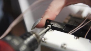 Woman twists screw assembling detail of refrigerator