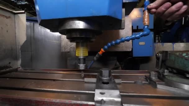 Worker adjusts cooling pipe on drilling machine tool in shop — Stock videók