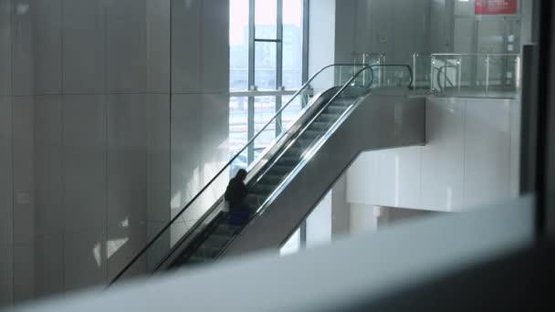 Turista hátizsák liftek fel mozgólépcső a repülőtér csarnokában — Stock videók