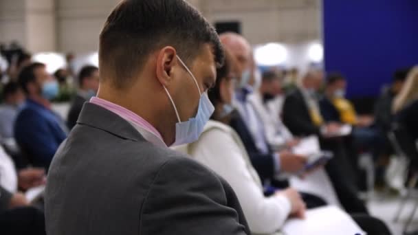 Businessman with medical mask writes at business conference — Stock Video