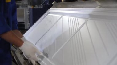 İşçi fabrikadaki evcil buzdolabının plastik detaylarını kontrol ediyor