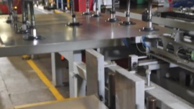 Manipülatör metal levhayı alır ve fabrikada konveyör takar