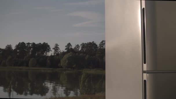 Stylová domácí lednice stojí na břehu klidného jezera — Stock video