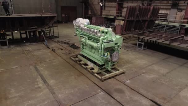 Цветной завернутый двигатель на полу и рабочий на отремонтированном корабле — стоковое видео