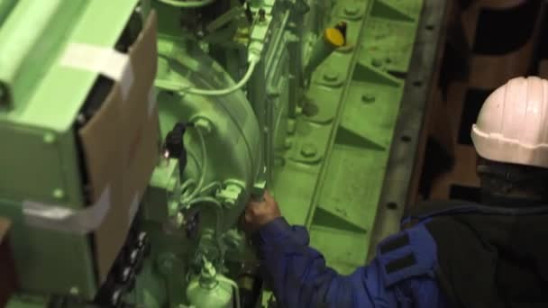 Квалифицированный сотрудник проверяет новый двигатель, установленный в трюме корабля — стоковое видео