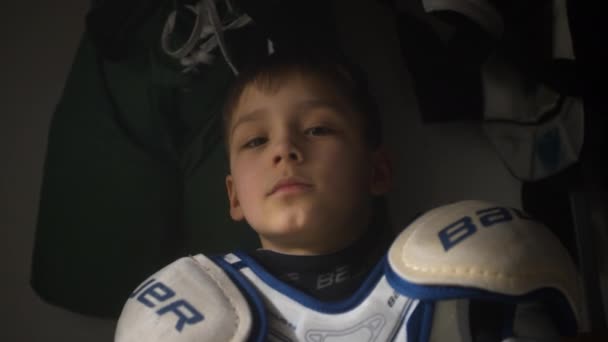 Giocatore di squadra di hockey ragazzo con protezioni alle spalle nello spogliatoio — Video Stock