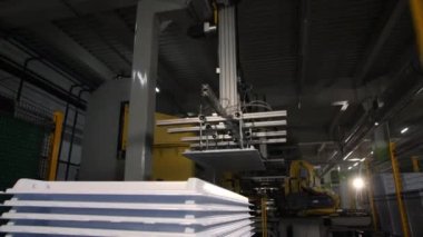 Mekanik kol plastik buzdolabı parçalarını dükkana yığar.