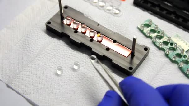 Arbeidstaker setter linser på kjøleskap med lamper ved bordet – stockvideo
