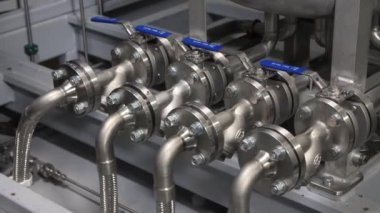 Flanşlı borular ve parlak ışıklandırılmış atölyede mavi kollar.