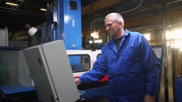 Grå hårig arbetare vid kontrollpanelen av maskinen i verkstaden — Stockvideo