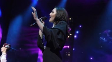 Siyah elbiseli güzel kadın konserde sahnede şarkı söylüyor.