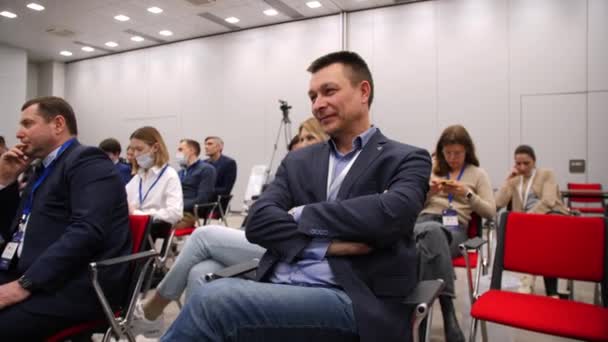 Happy businessman sits listening to lecture at conference — Stock Video