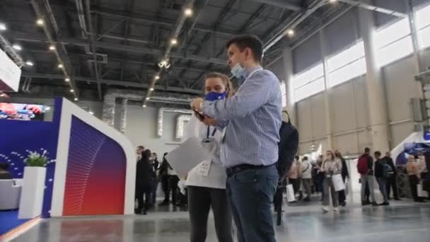 Woman and man with medical masks and papers at exhibition — Stock Video