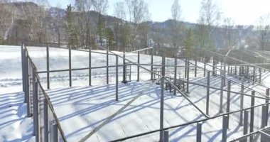 Metal kirişlerle taçlandırılmış dayanıklı çelik yapı karlı yamaçlara hükmediyor. Güneş ışığı altındaki parlak ağaçlar parlak dağ zarafeti getirir.