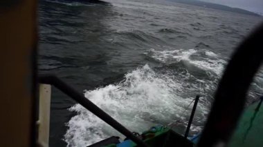 Dalgalar, havada köpük saçan gemilere ritmik bir şekilde çarpar. Sprey soluk ışık altında parıldarken gemi çalkantılı sularda hareket ediyor.