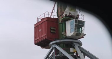 Rıhtımın üstünde sağ tarafında parlayan büyük vinç kuleleri var. Endüstriyel dev bulutlu gökyüzü kollarının altında duruyor.