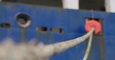 Kalın halat, deniz sisinden ıslanmış çelik şahin deliğinden geçiyor. Fare bekçilerinin parlak çemberi küçük bir düzen sembolü gibi göze çarpar.