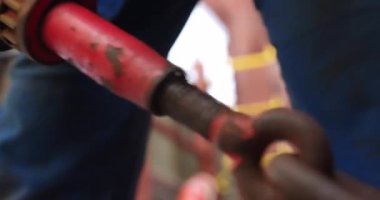 İşçi, kargo gemisindeki ağır zincirleri birbirine bağlayan vidaları kapatıyor. Kalifiye denizci rıhtıma demir atarken ağır metal çapa takıyor.