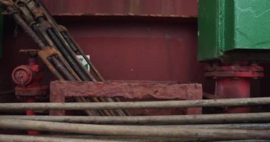 Eldivenli işçiler güvertede yıpranmış metal parçaları topluyor. Denizci gemi üzerinde çalışan büyük göz cıvataları ayarlar.