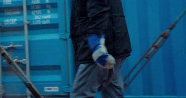 ALMATY, KAZAKHSTAN - 09 Ekim 2025: Liman işçisi sonsuz renkli konteynırların yanında güvenli adımlar atıyor. Metal duvarlardan yansıyan ince ışık karamsar bir sakinlik yaratır.