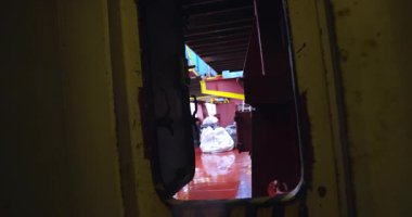 Yağmurla ıslanmış eşik ışıldayan yüzeye açılıyor. Islak güverte gri ışık altında parlar. Çelik kapı sallanıyor damlayan seslerin arasında