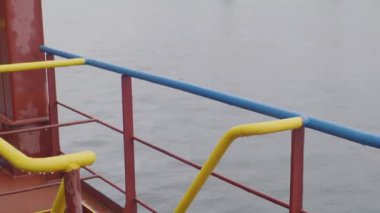 Miğferli bahriyeli, metal merdivenlerden loş kargo bölmesine, nemli deniz havasına iniyor. Miğferli işçiler alt güverteye hareket ediyor