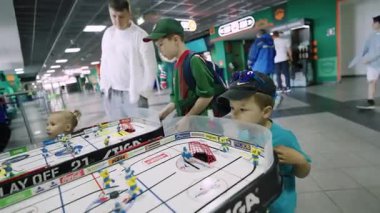 ALMATY, KAZAKHSTAN - 27 Kasım 2025: Çocuklar salonda renkli plastik figürler kullanarak yaratıcı hokey simülasyonu oynuyorlar. Hayalperest an, geniş ve canlı stadyumun içini dolduruyor.