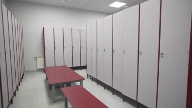 Düzenli soyunma odasında sağlam dolaplar ve şık banklar var. Çalışma öncesi rutinler sırasında aydınlatma formları dengeli ortam