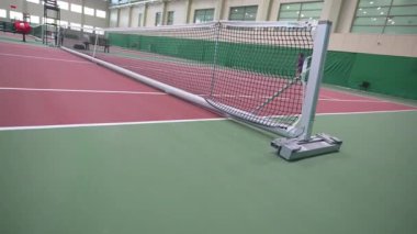 Sert ağ, geniş bir hava sahası içinde, parlak ışık altında düz bir çizgide duruyor. Pürüzsüz kontrollü ortam dikkatli ritmik hareketi destekler