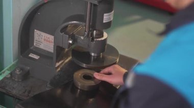 Adam metal yıkama makinesini endüstriyel baskı makinesine yerleştiriyor. Üretim ortamı mekanik doğruluğu vurguluyor