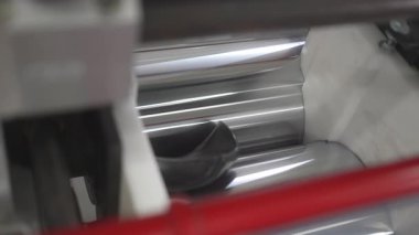 Kesik lastik parçaları endüstriyel geri dönüşüm sırasında dönen metal silindirler arasında kayboluyor. Ağır makineler kauçuk sıkıştırması yapar