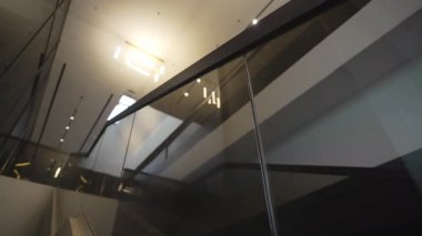 Renkli cam korkuluklar tavan avizelerini yansıtıyor ve zarif bir görsel ritim yaratıyor. Pürüzsüz yüzeyler ışık derinliğini ve modern atmosferi yükseltir.