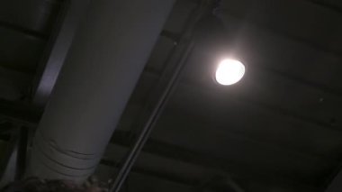 Eldivendeki teknisyen, sahne ışıklarını yakın çekimde ayarlar. Çalışan, yarı karanlık bir ortamda ışığın parlaklığını yönetir.