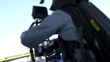 ALMATY, KAZAKHSTAN - 28 Eylül 2025: Kameraman ve meslektaşları dışarıda modern kamerayla çalışıyor. Profesyonel ekip şehir caddesinde çekim yapıyor. Film yapma süreci