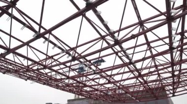 Metal yapısal çerçeve, görünür kiriş eklemli aktif inşaat aşamasını gösteriyor. Sahne teknik ve dinamik hissettiriyor