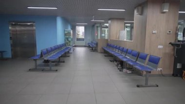 Konforlu özel klinik lobisinde düzenli sıra sandalyeler ve kahve makinesi bulunuyor. Parlak asansör sakin bir tıbbi ortam yaratır.