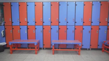 Çeşitli sıra dolaplar, kısıtlı soyunma odası duvarlarına tezat oluşturarak görsel ritim yaratıyor. Tasarım dengeli ve canlı görünüyor