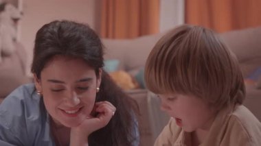 ALMATY, KAZAKHSTAN - Mayıs 07 2025: Kadın yerde çizim sırasında erkeğin yanında gülümsüyor. Kadın çalışmalar ilerlemeyi cesaretlendirirken erkek kalem eklemeyi iyi biliyor