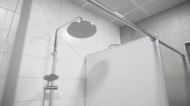 Yuvarlak başlıklı duş başlığı, temiz fayanslı kamusal alanda nazikçe parlıyor. Yumuşak dağınık yansımalar rahatlatıcı bir atmosfer yaratır.