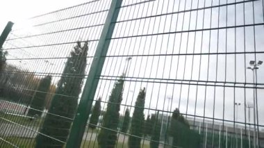 Yeşil ağ çiti, yumuşak gökyüzüne doğru hafif bulutlarla uzanıyor. Minimum bileşim açıklık ve açık hava atmosferini vurgular